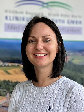 Jasmin Hirz-Weidinger Porträt einer lächelnden Frau mit schulterlangem, dunklem Haar, in weißem Strickpullover. Sie blickt direkt in die Kamera vor unscharfem, nebensächlichem Hintergrund. Schwerpunkt: freundliches Porträtfoto.